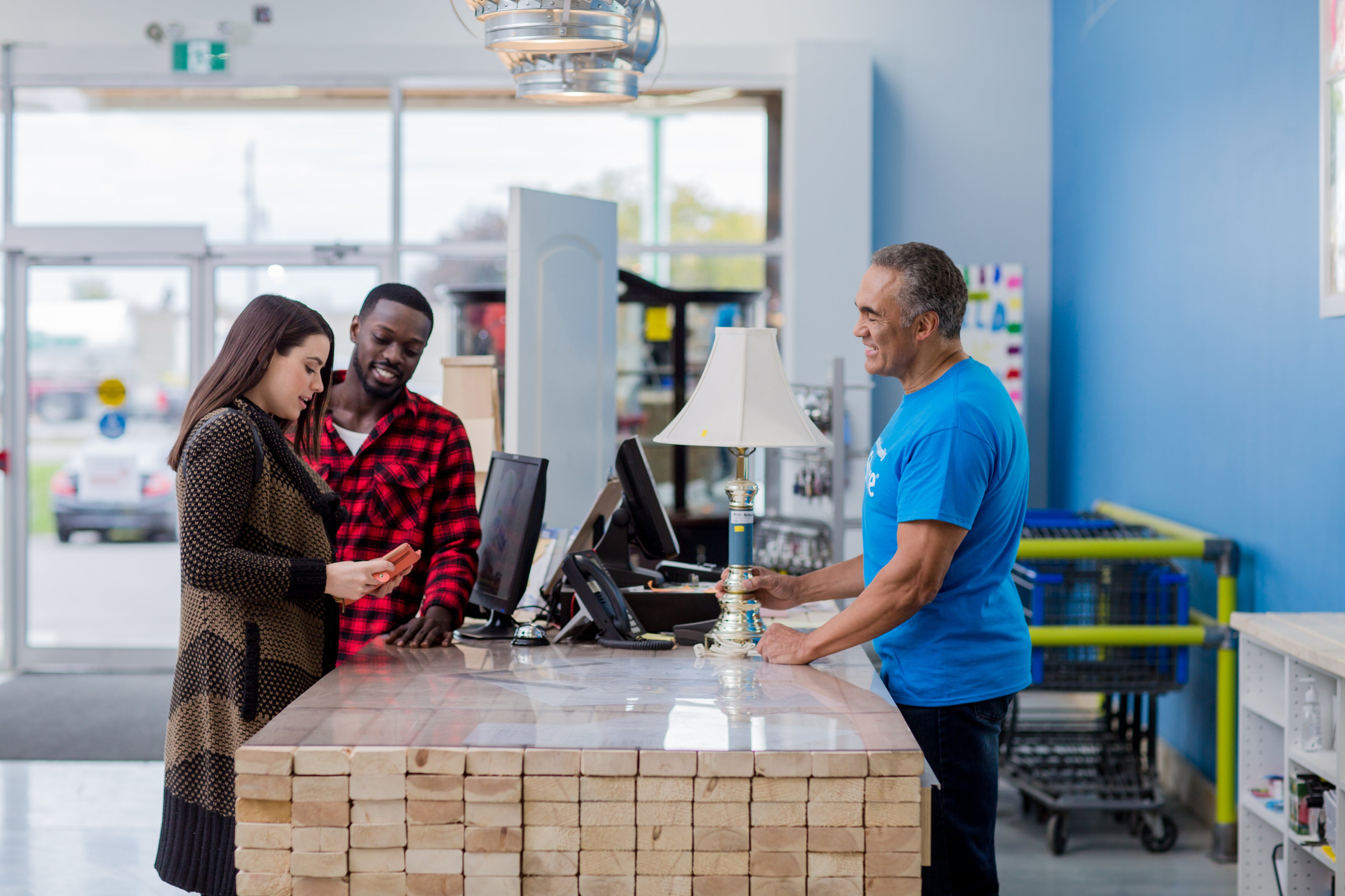 Customer service interaction at a store with a customer and employee at the counter.