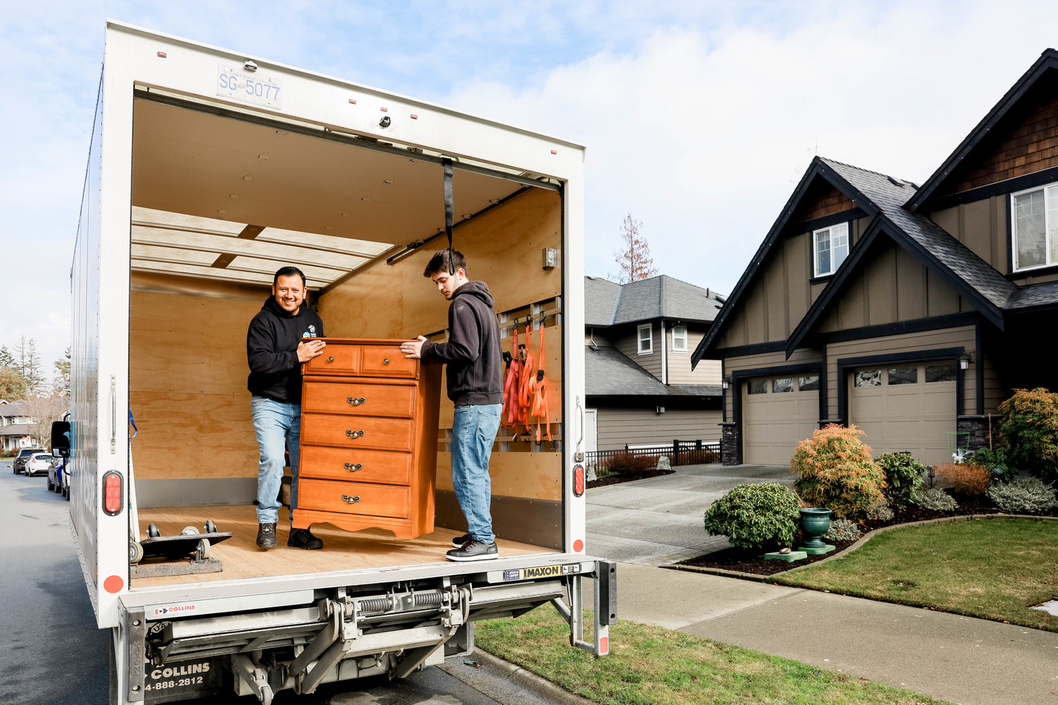 Two men loading furniture into a moving truck in a residential area.